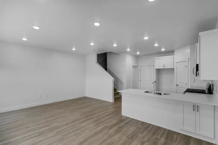 Open-concept living space featuring wood-finish flooring, recessed lighting, and a kitchen island with an integrated sink