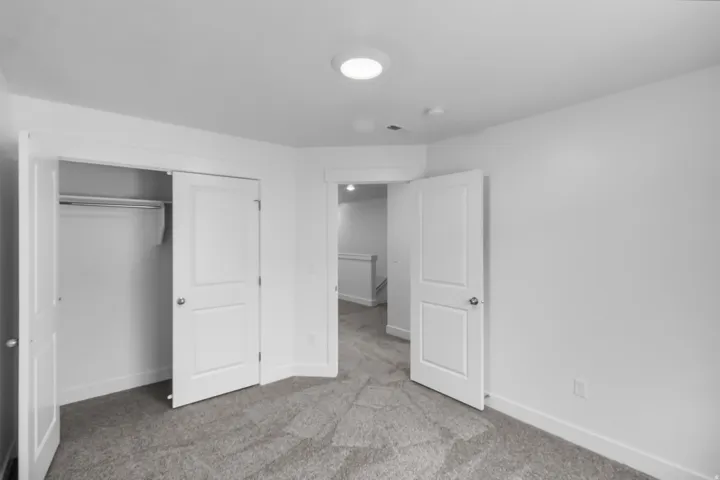 Neutral gray carpeting, white trim, and a white interior door