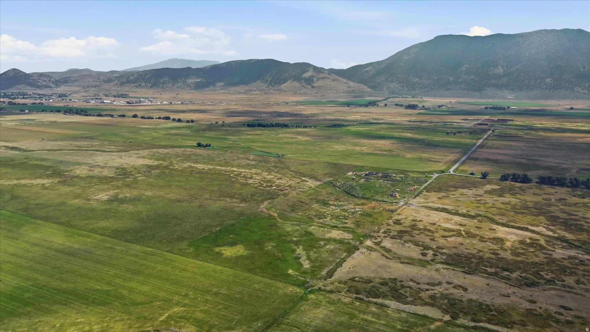 Expansive land parcel with varied natural terrain, featuring distant mountain ranges and a visible roadway