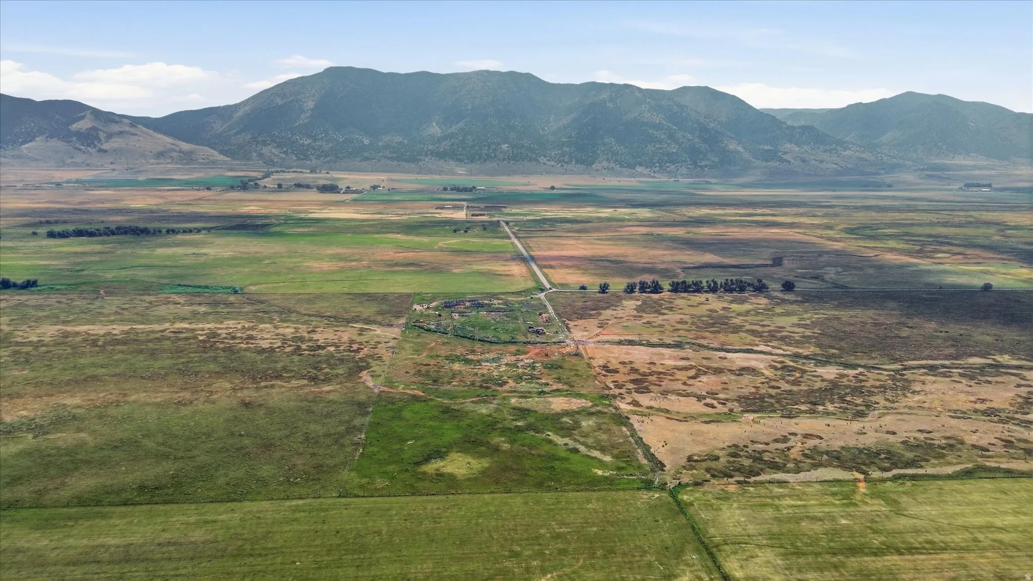 Expansive land parcel featuring open fields, distant mountains, and a visible access road