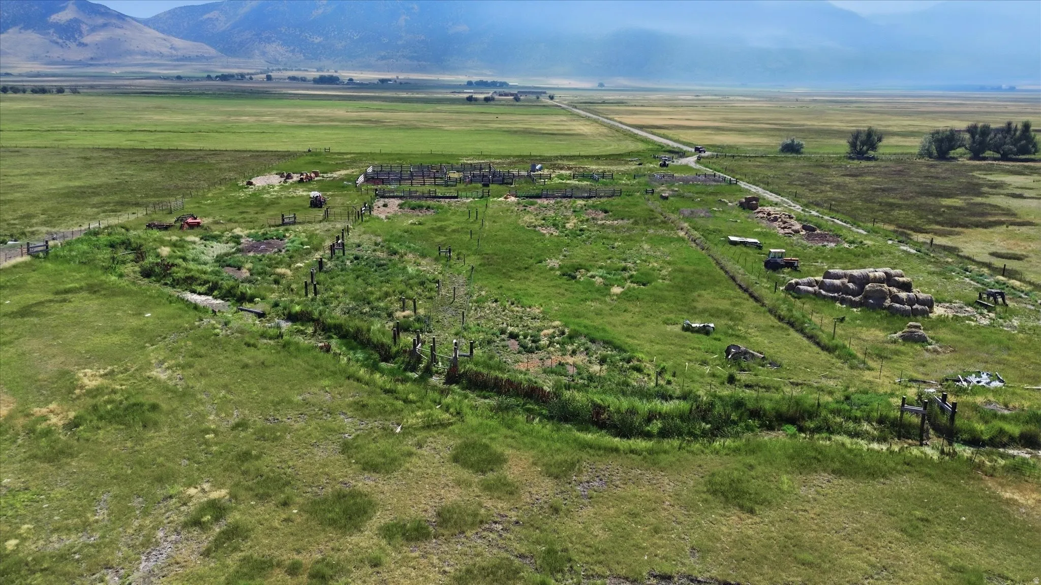 Expansive acreage with natural terrain, distant mountainous backdrop, and established dirt pathways