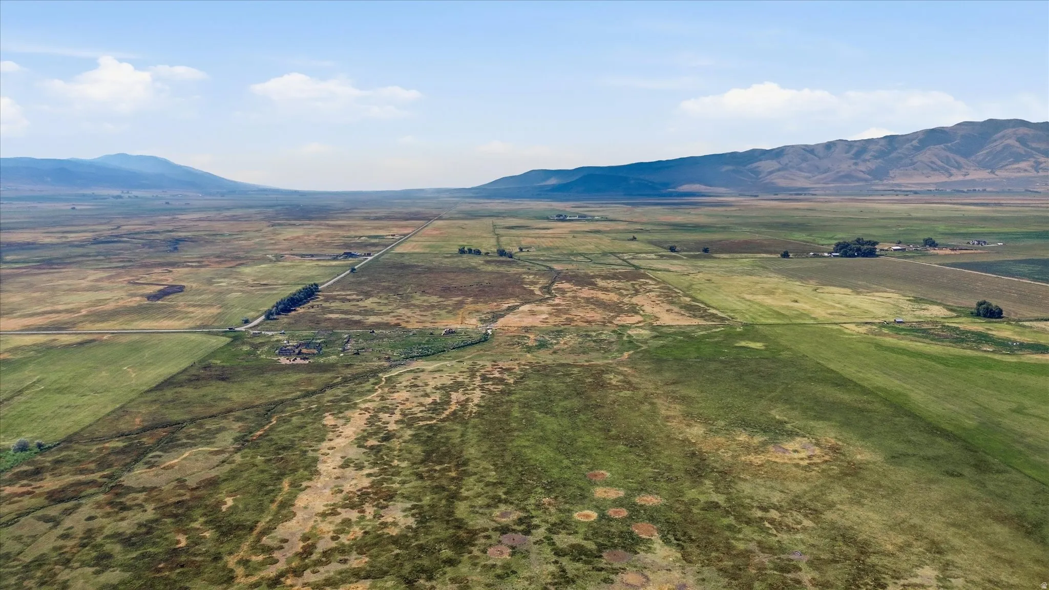 Expansive agricultural land featuring cultivated fields and a distant mountain backdrop