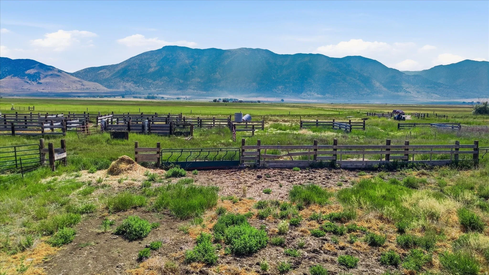 Expansive agricultural land featuring a series of perimeter fencing and corrals with mountain backdrops