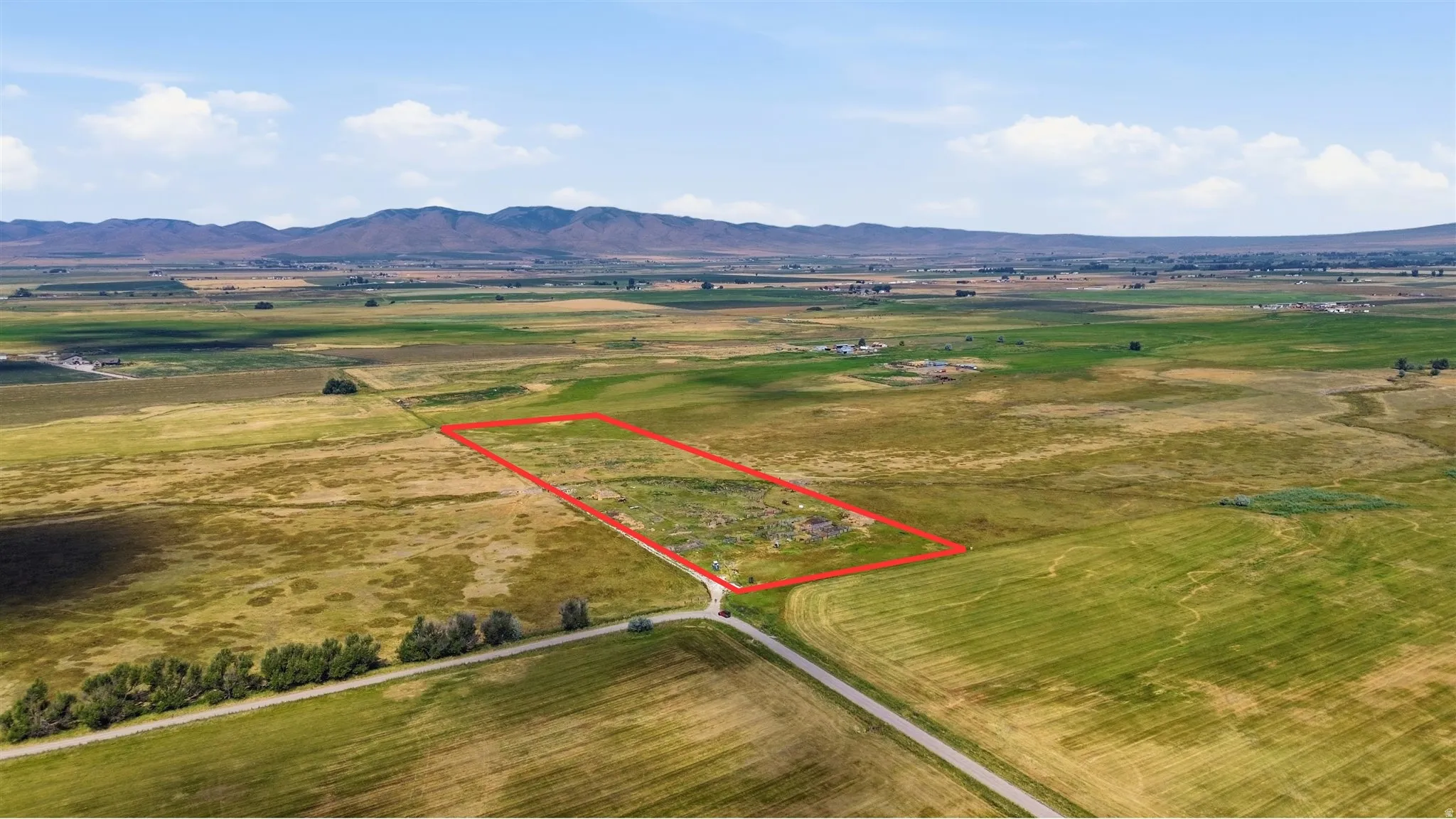 Expansive rural property featuring a defined boundary, a gravel road, and surrounding agricultural fields