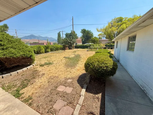 Expansive outdoor space featuring mature shrubs, a concrete walkway, and a distant mountain backdrop