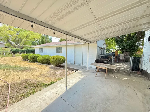 Covered patio with concrete flooring, supported by metal posts