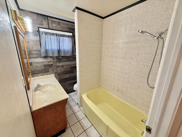 Vanity with integrated sink, wood-finish cabinetry, and wall-mounted light fixture