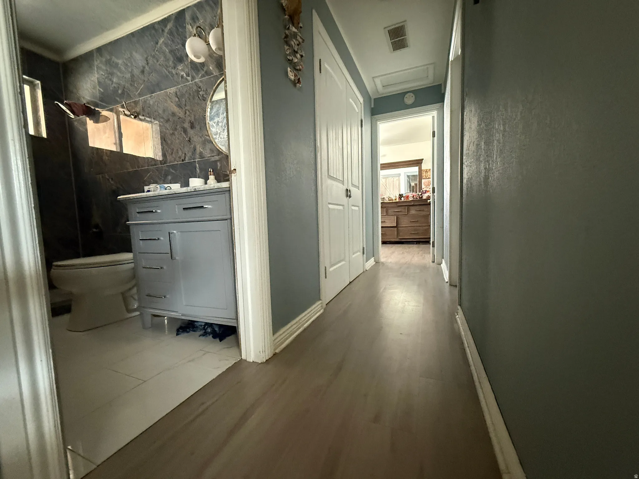 Hallway featuring wood-finish flooring and white bi-fold doors
