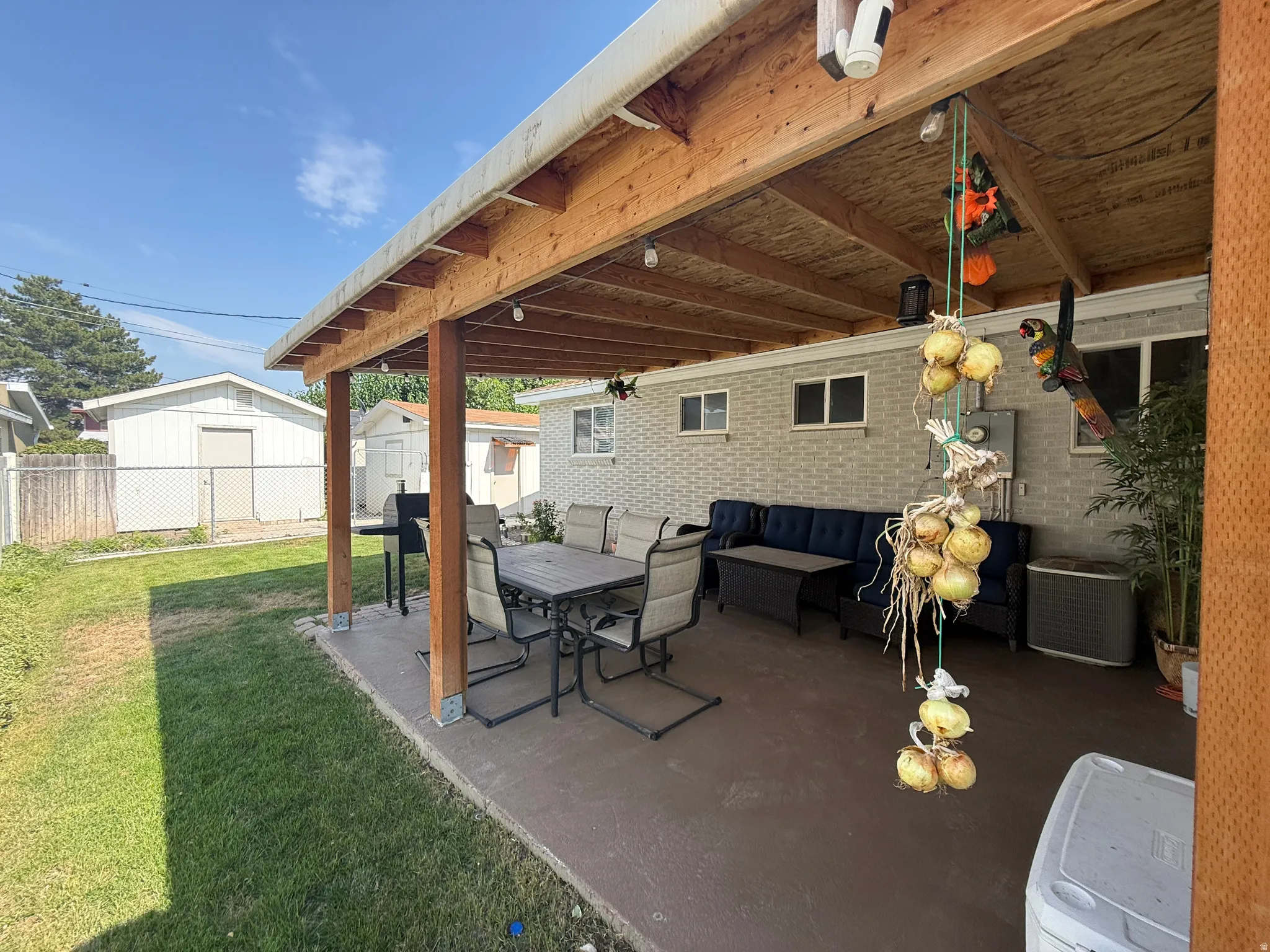 Covered patio with exposed wood beam ceiling, concrete flooring, and brick exterior
