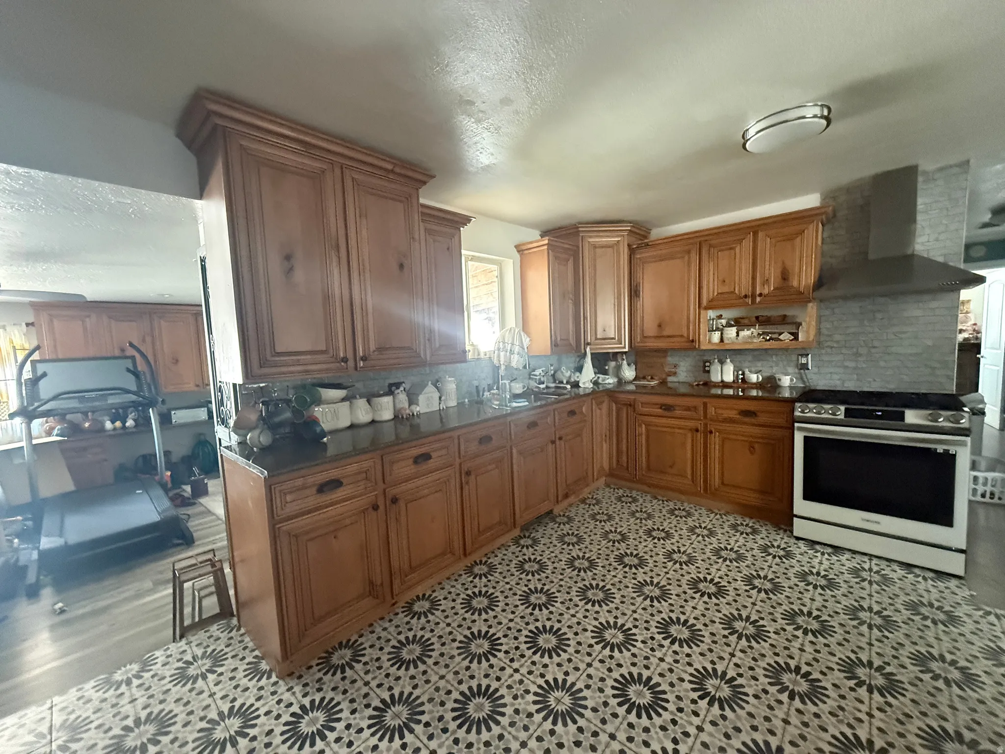 Expansive kitchen with wood cabinetry, dark countertops, and a patterned tile floor