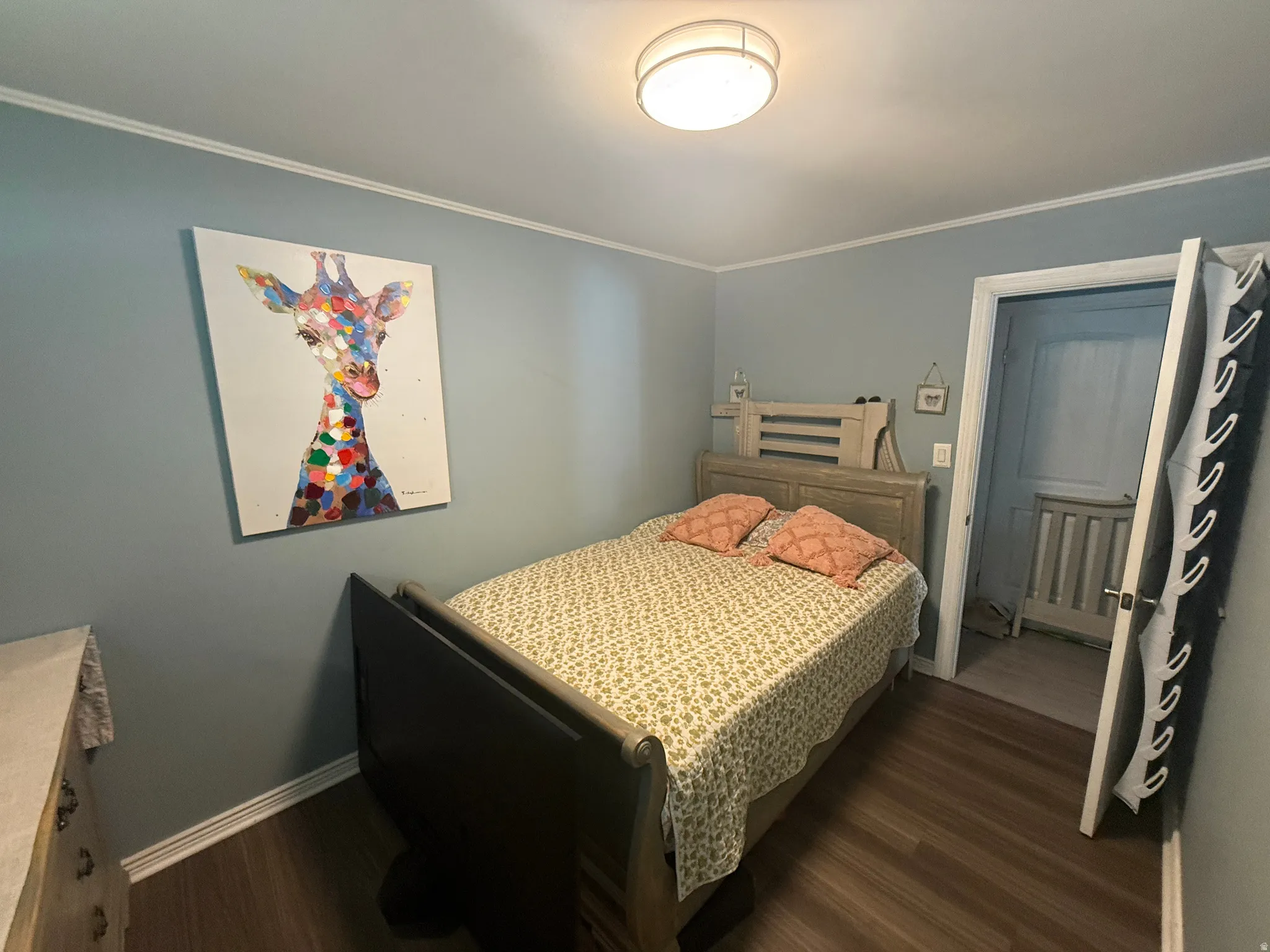 Wood-finish flooring, crown molding, and a flush-mount ceiling light fixture