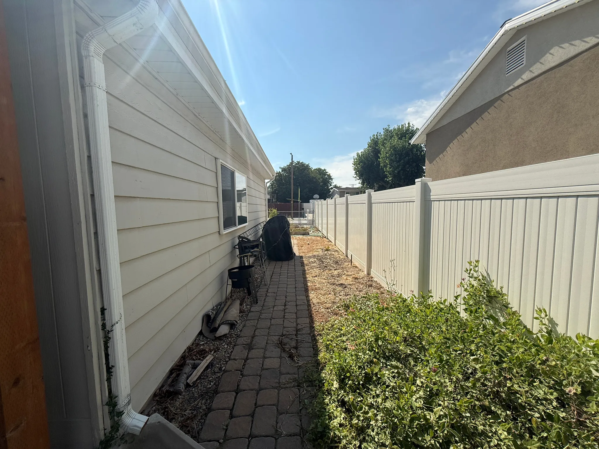 Exterior siding with multiple windows, paver walkway, and a privacy fence