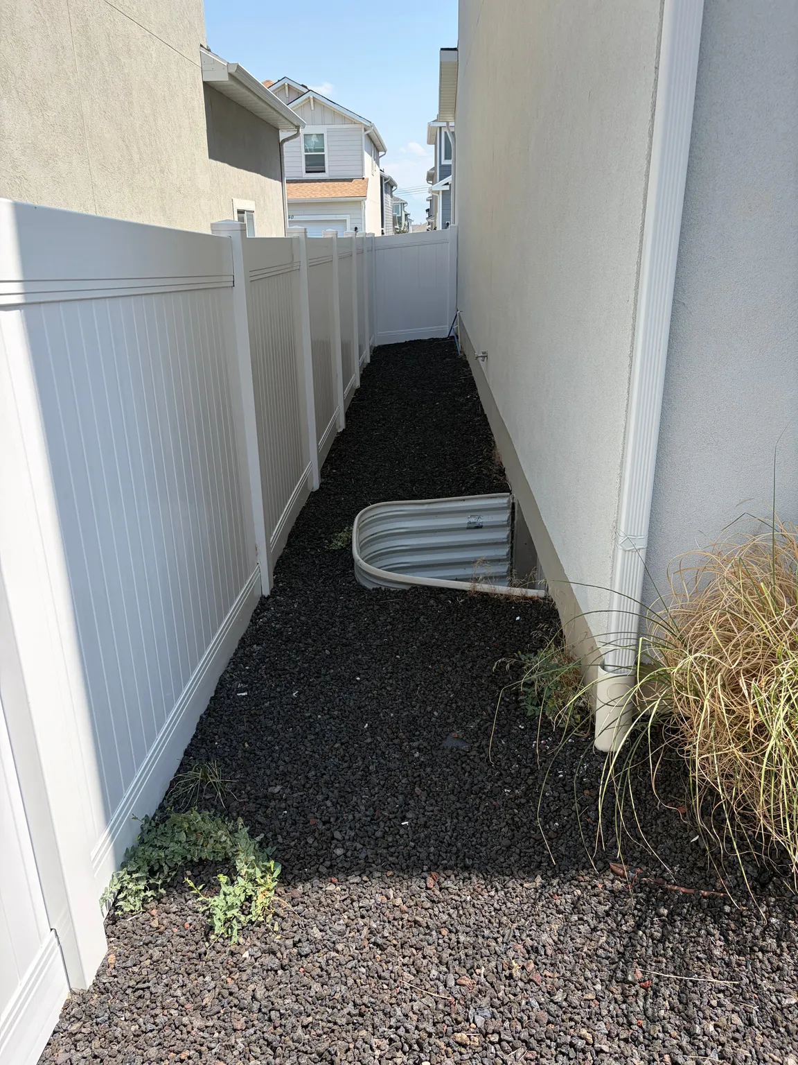 Vinyl privacy fencing surrounds a crushed rock landscaping bed