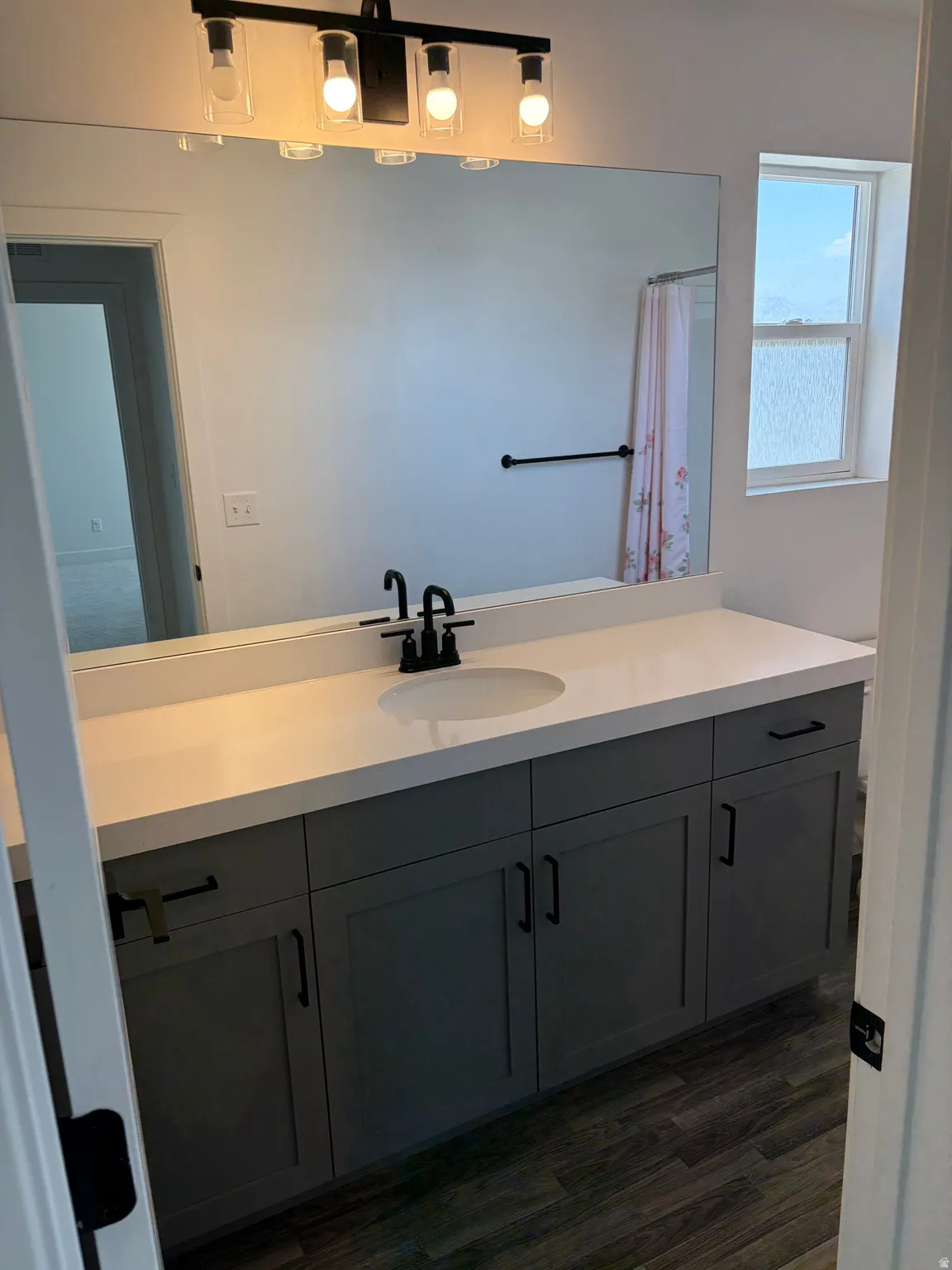 Vanity featuring a single undermount sink, a white countertop, and dark cabinetry with black hardware
