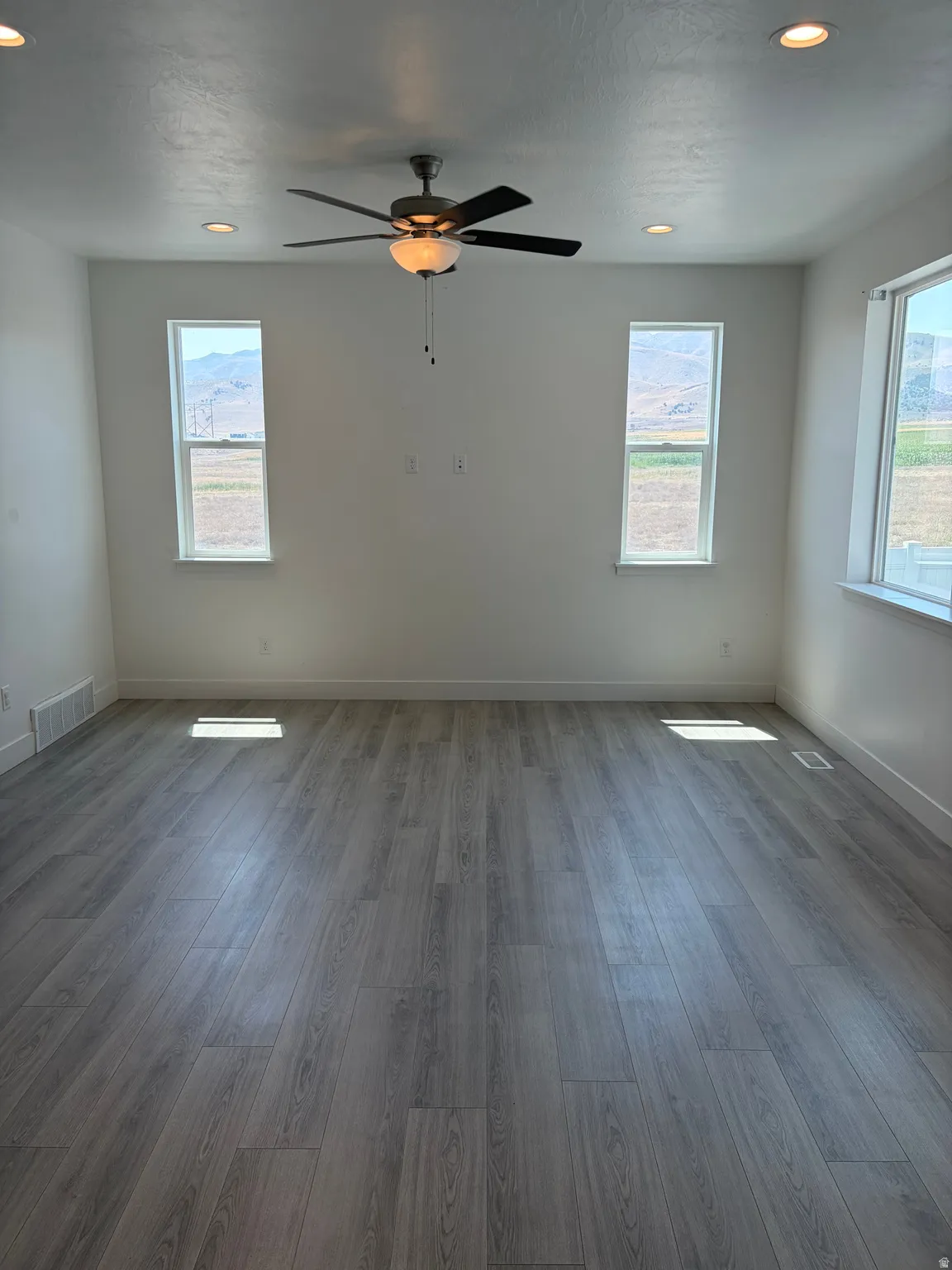 Wood-finish flooring with recessed lighting and a ceiling fan