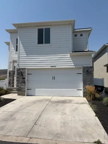 Two-story facade featuring white horizontal siding and stone accents