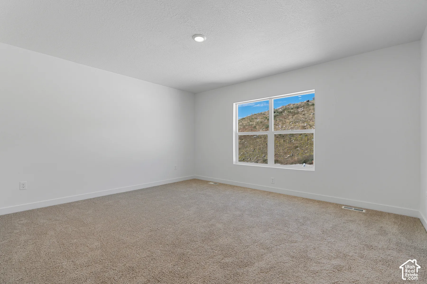 Recessed lighting, neutral wall finishes, and a window with mountain scenery