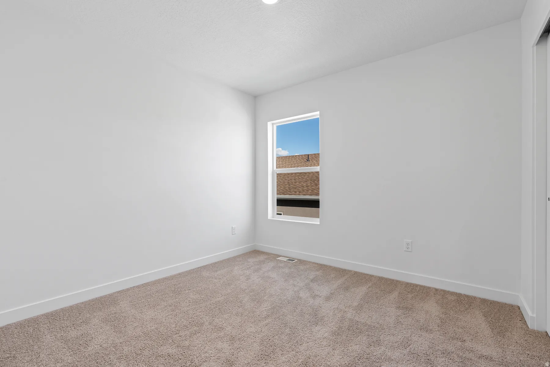 Carpeted flooring, single window, white walls, and a built-in closet