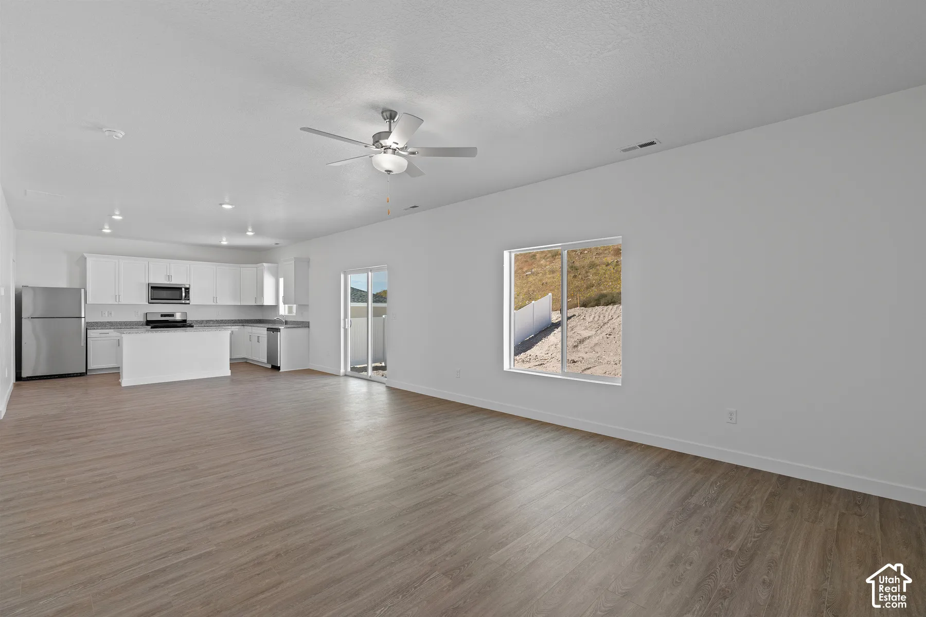 Open-concept living area featuring wood-finish flooring, recessed lighting, and a ceiling fan