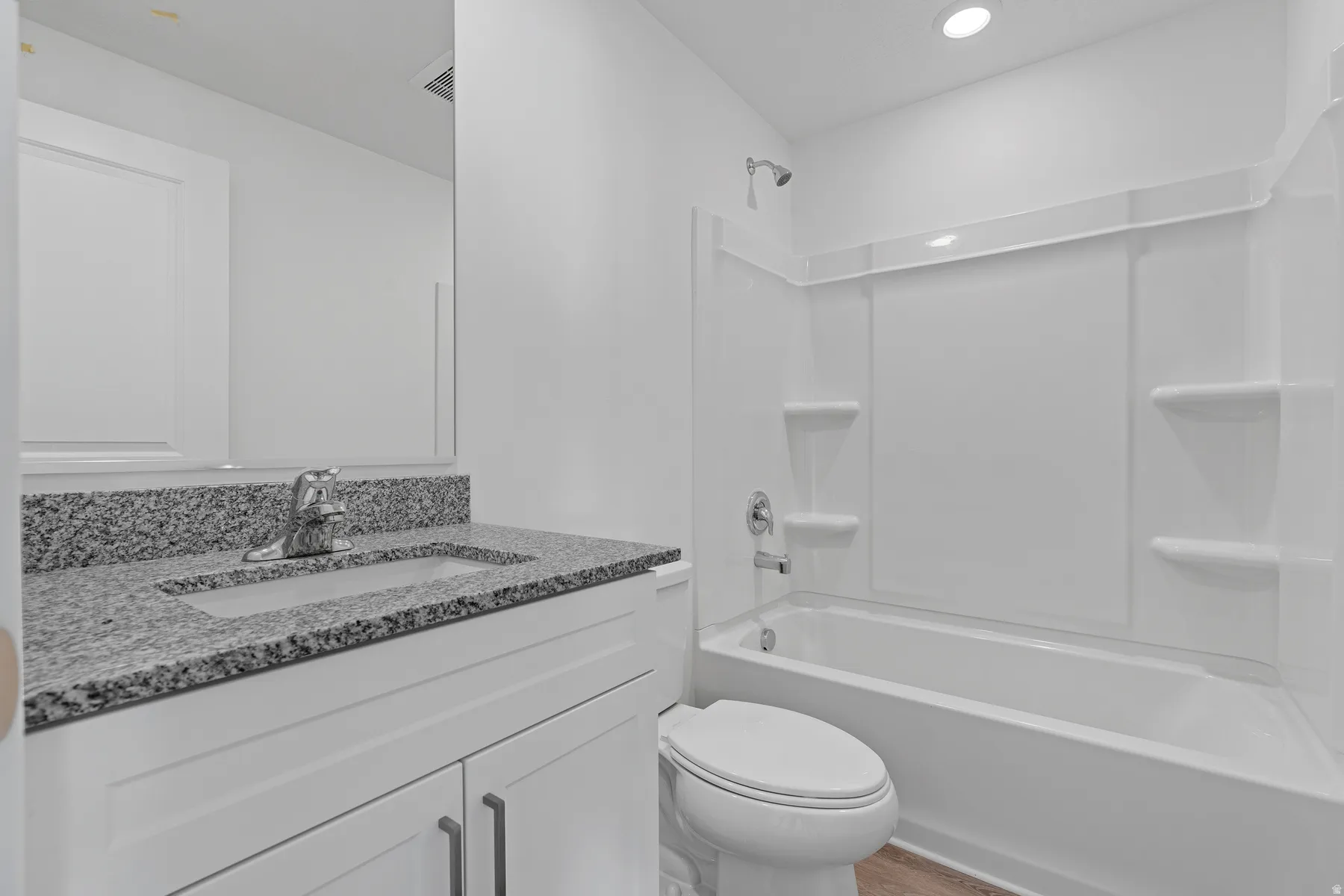 White vanity with a granite countertop, undermount sink, and chrome faucet