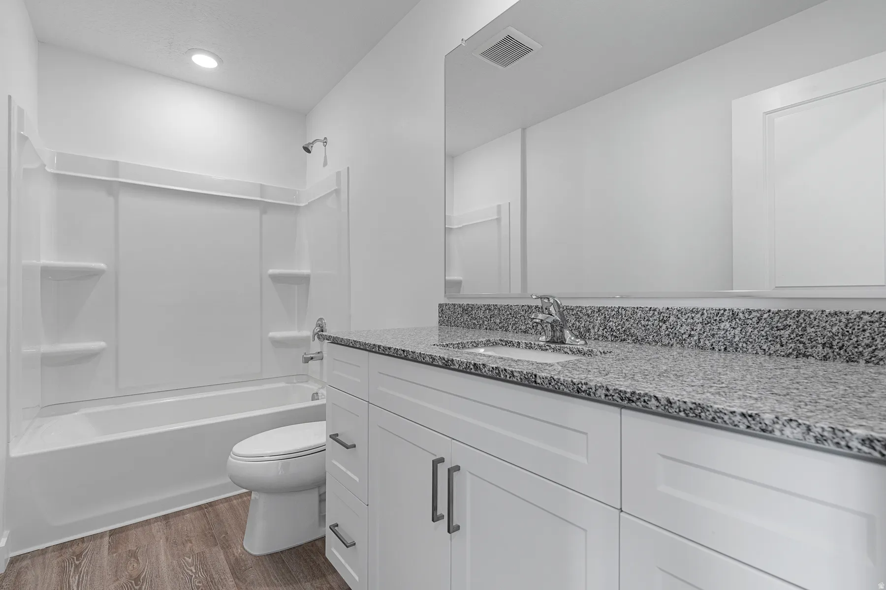 White shaker-style vanity with dark hardware, granite-style countertop, and integrated sink