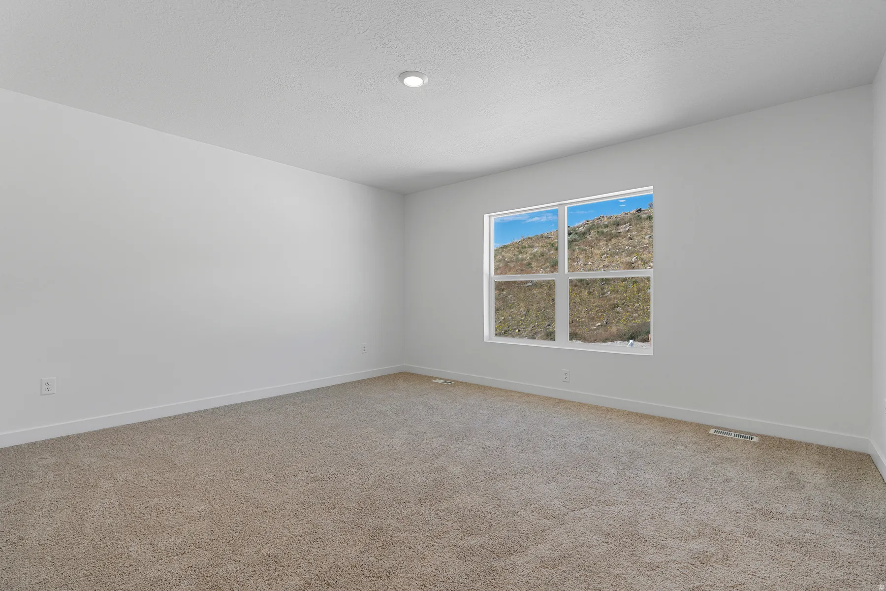 Recessed lighting, neutral wall finishes, and a window with mountain scenery