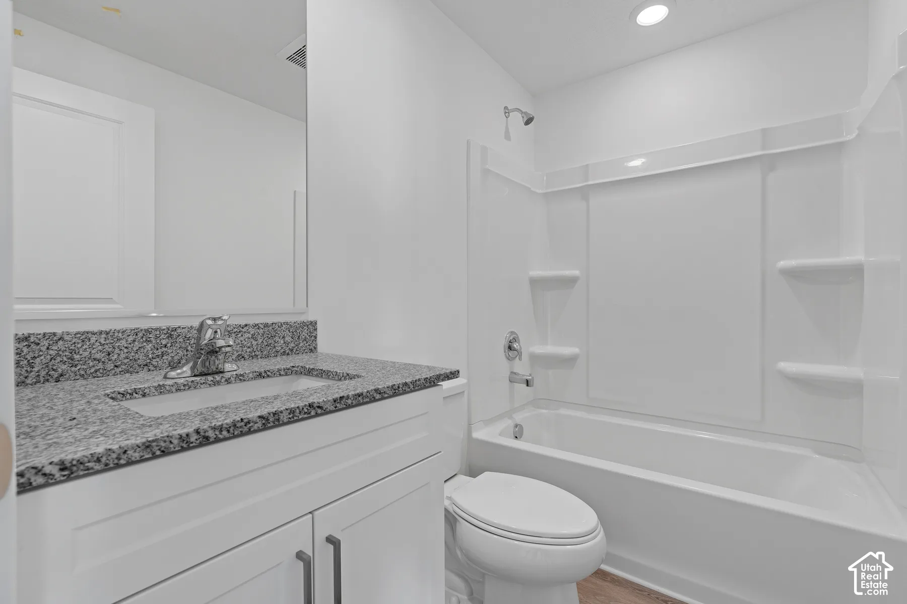 White vanity with a granite countertop, undermount sink, and chrome faucet