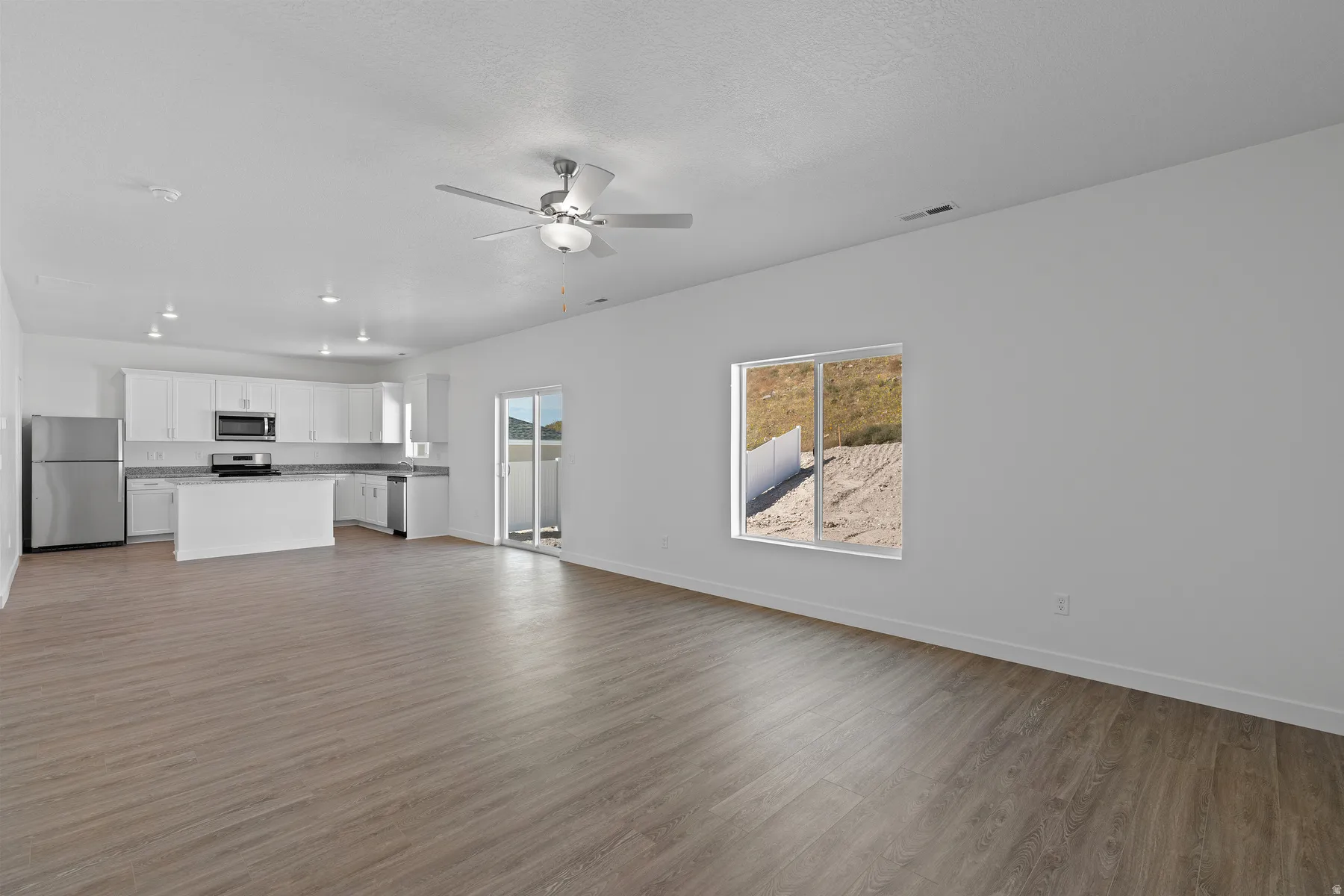Open-concept living area featuring wood-finish flooring, recessed lighting, and a ceiling fan