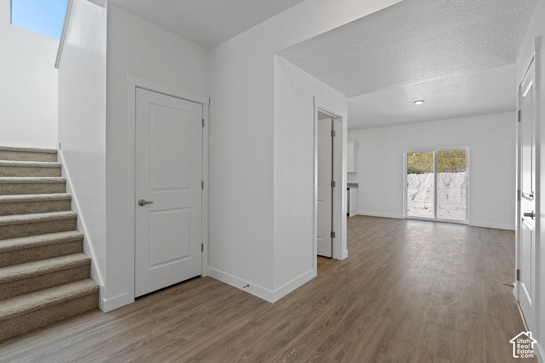 Carpeted staircase, wood-finish flooring, white paneled doors, recessed lighting, and sliding glass doors