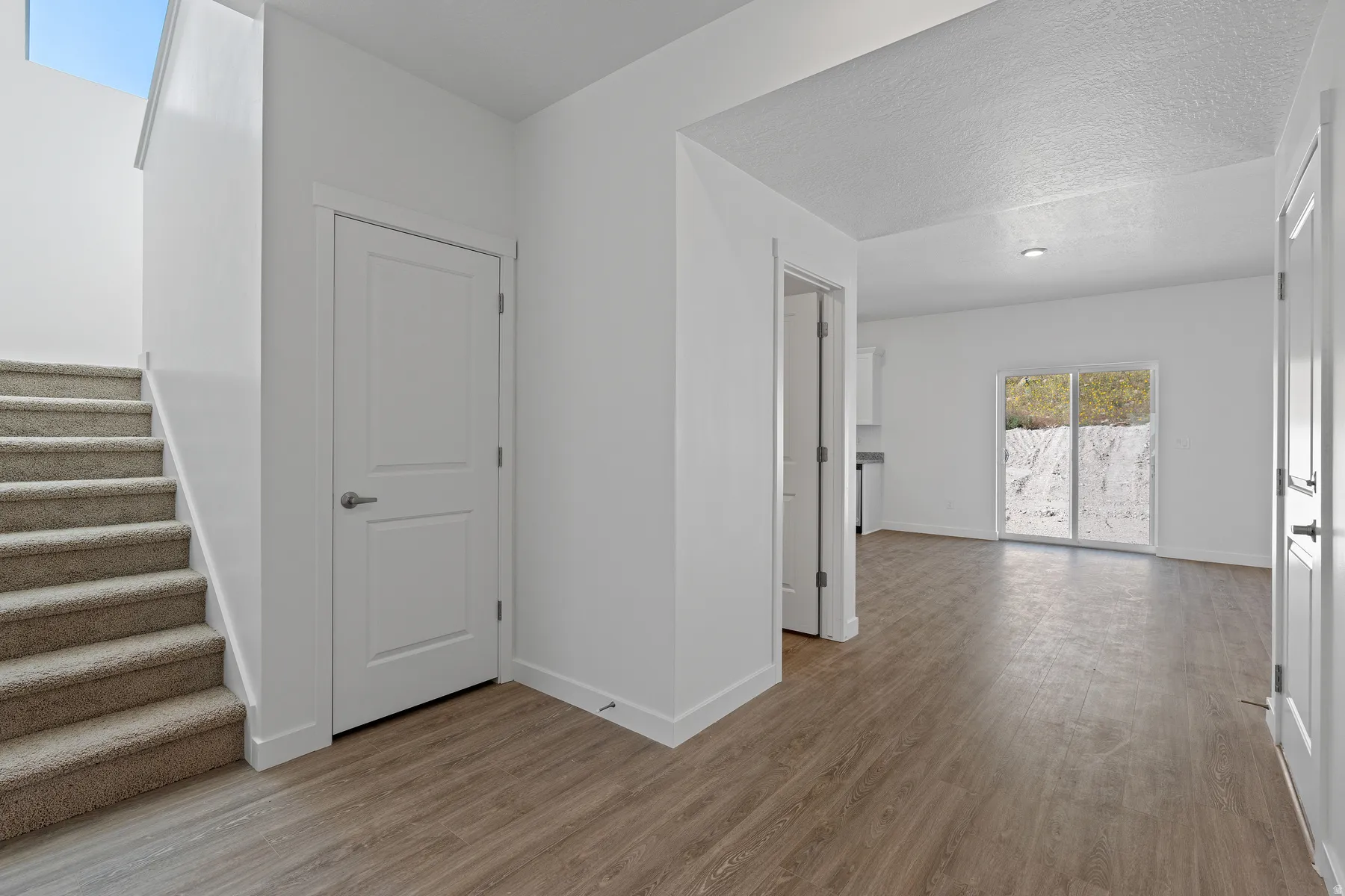 Carpeted staircase, wood-finish flooring, white paneled doors, recessed lighting, and sliding glass doors