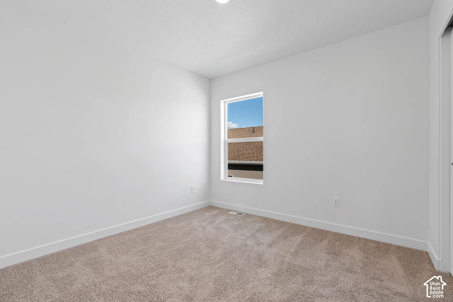 Carpeted flooring, single window, white walls, and a built-in closet