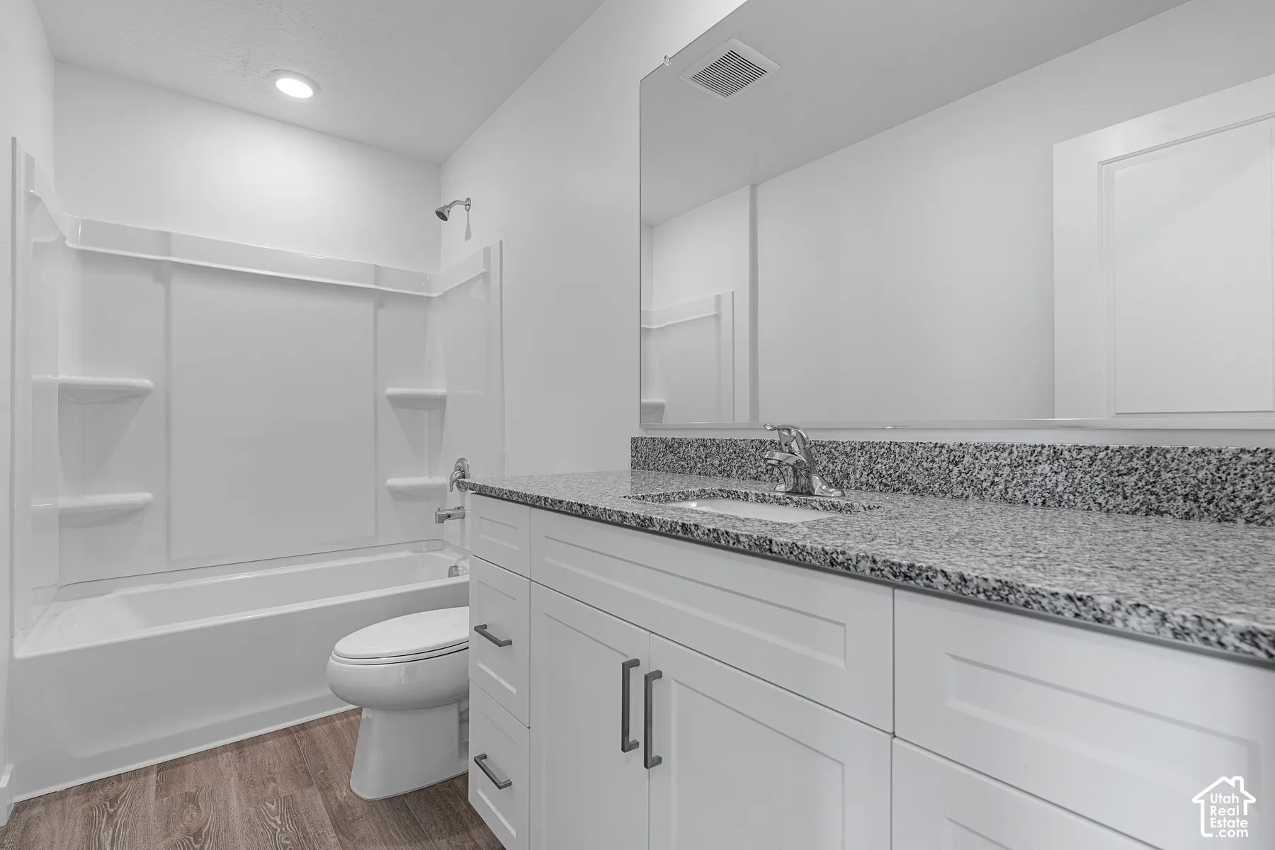 White shaker-style vanity with dark hardware, granite-style countertop, and integrated sink