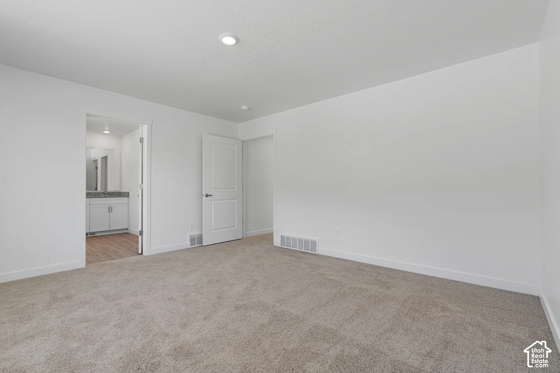 Neutral-toned carpeting, recessed ceiling lighting, and a two-panel interior door