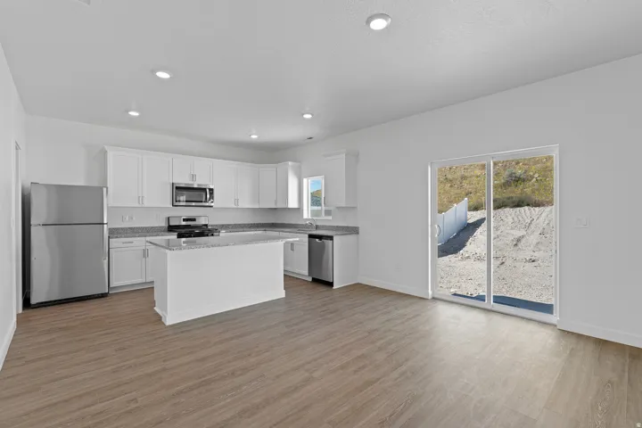 Open-concept kitchen with white cabinetry, stainless steel appliances, granite countertops, and a central island