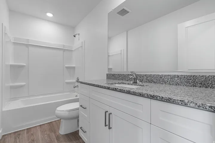 White shaker-style vanity with dark hardware, granite-style countertop, and integrated sink