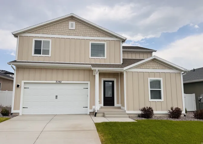 Two-story exterior with light-colored siding, contrasting dark entry door, and integrated garage