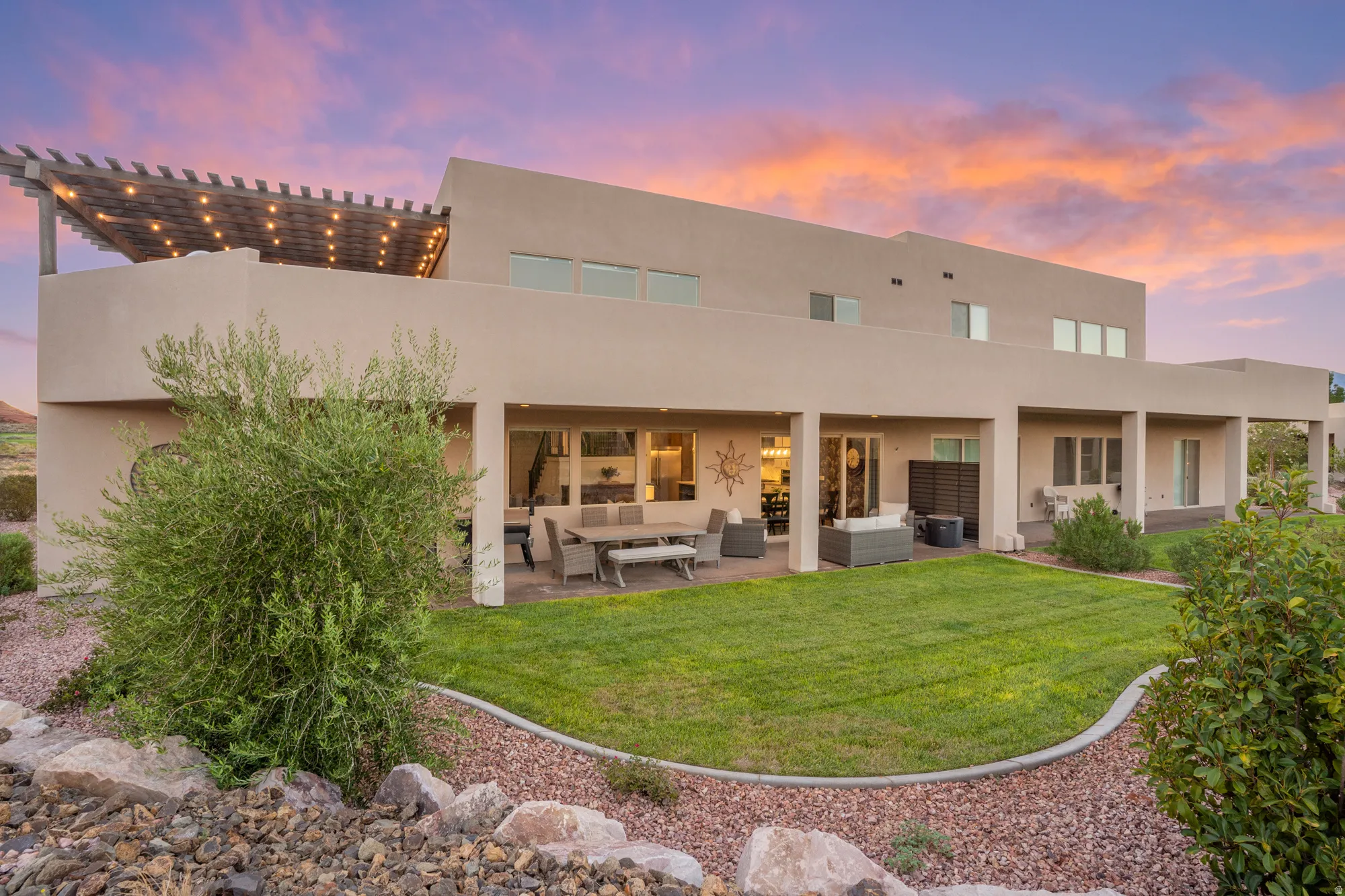 Terraced backyard with a patio, covered outdoor living space, pergola, and manicured lawn