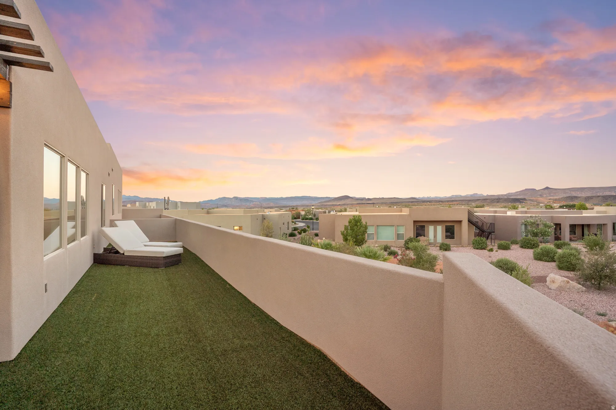 Rooftop deck featuring artificial turf, plaster walls, and a glass safety barrier