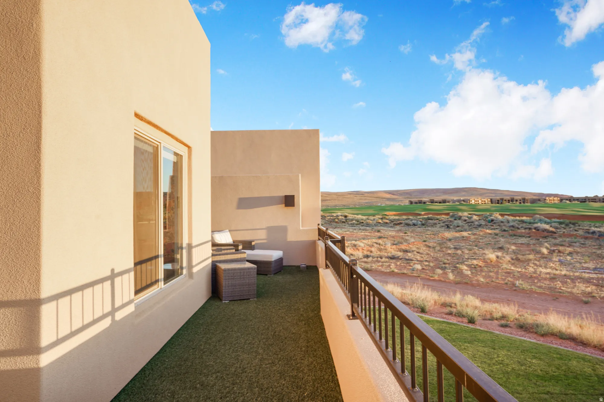 Balcony with artificial turf flooring, a metal railing, and a sliding glass door