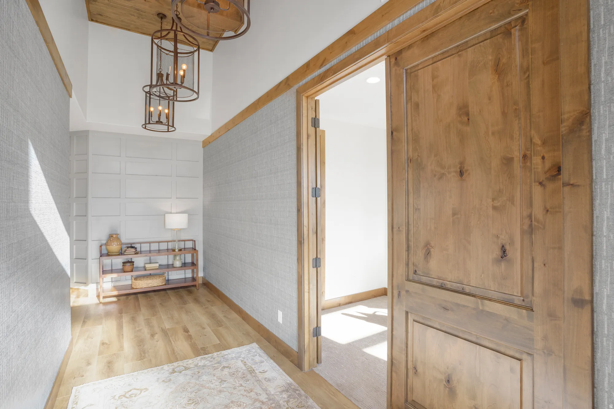 Hardwood-finish flooring, textured wall coverings, board and batten wall detailing, and a two-tier chandelier