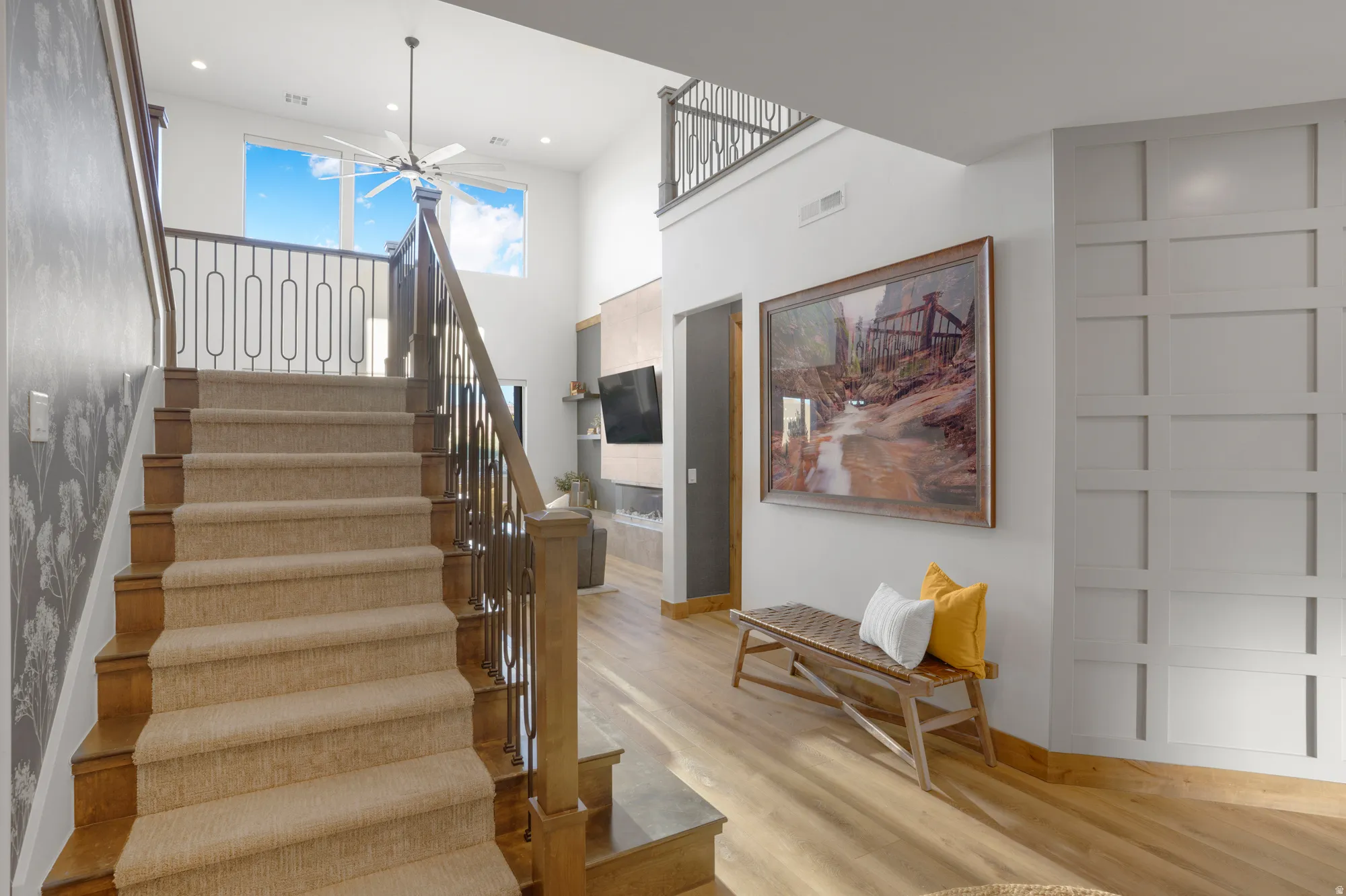 Staircase featuring wood risers, carpeted treads, and an open railing with decorative metal spindles