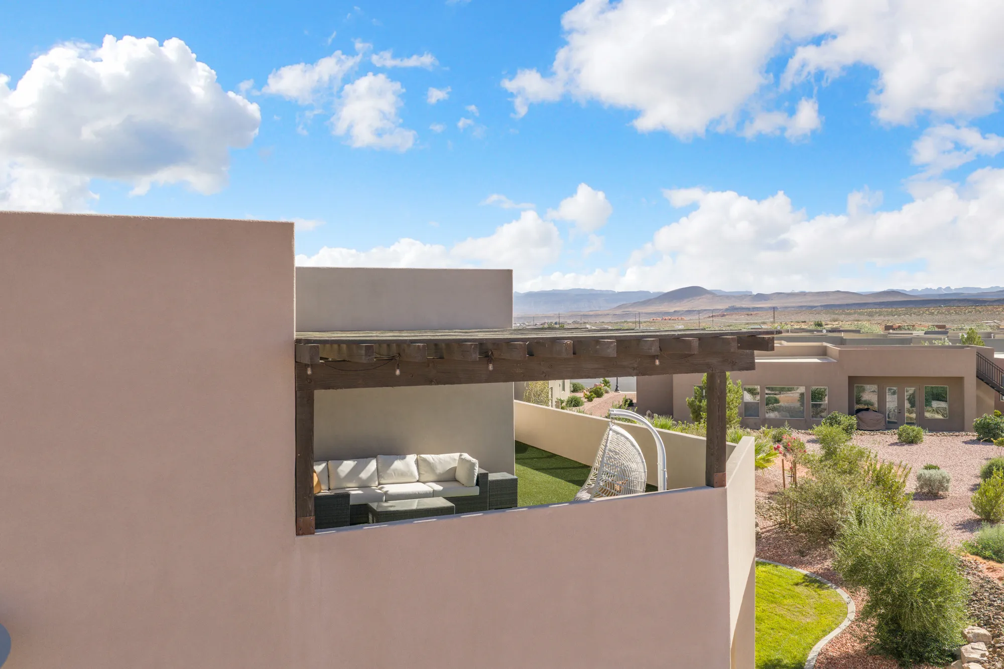 Terrace with a wood pergola, artificial turf, and stucco walls