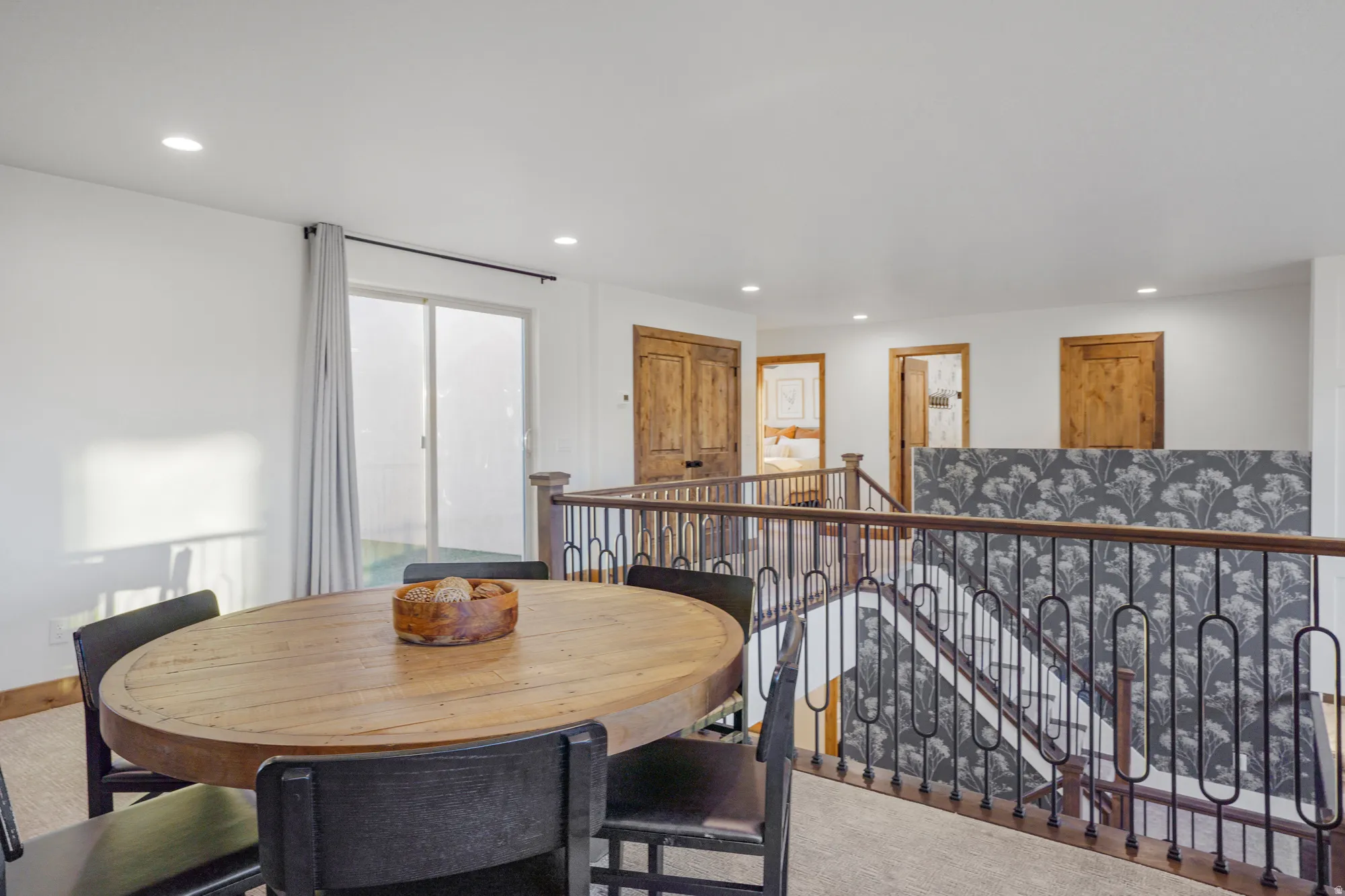Loft area featuring a sliding glass door, recessed lighting, wood-finish doors, and an iron baluster railing