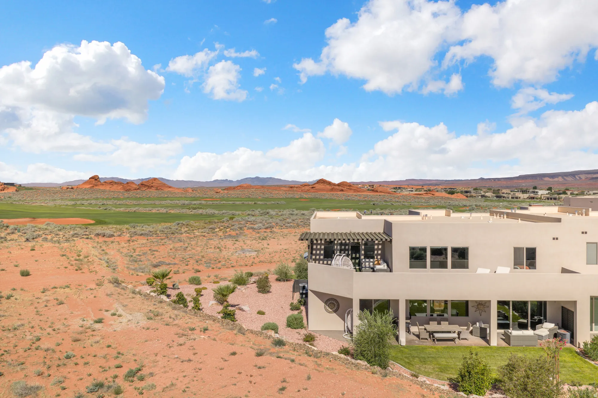 Contemporary exterior with multiple balconies and patios, featuring a desert landscape with distant red rock formations and a green expanse