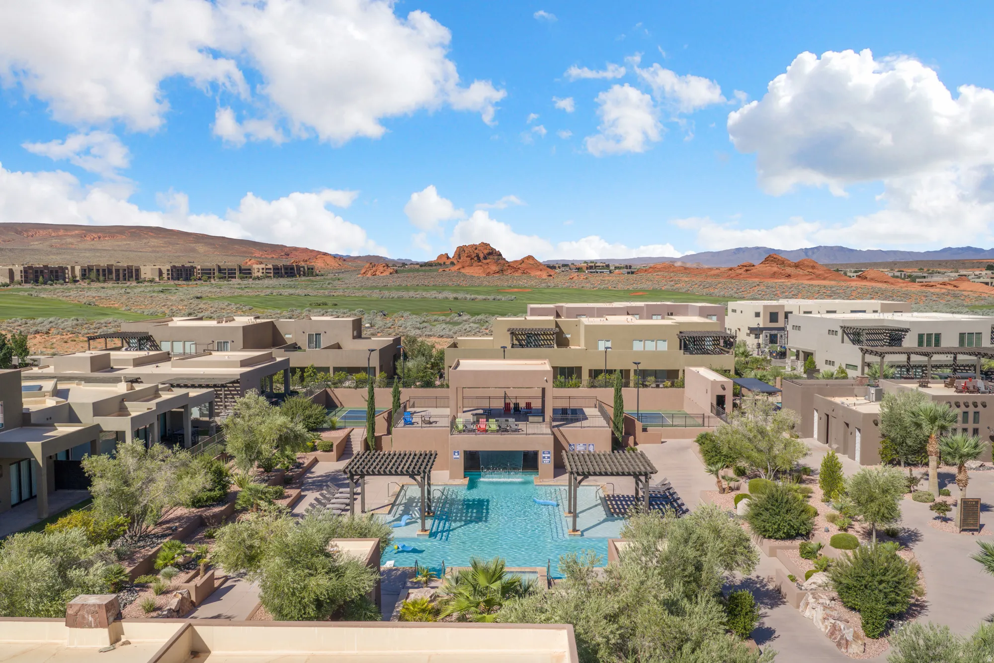 Outdoor swimming pool with integrated spa and decorative pergola structures, surrounded by desert-adapted landscaping