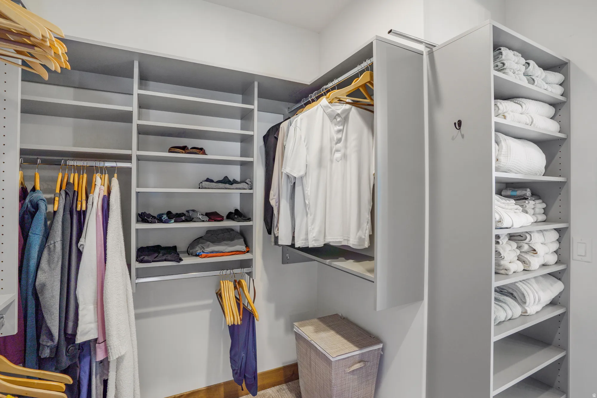Custom closet system featuring multiple shelving units, integrated hanging rods, and a tall storage tower with adjustable shelves
