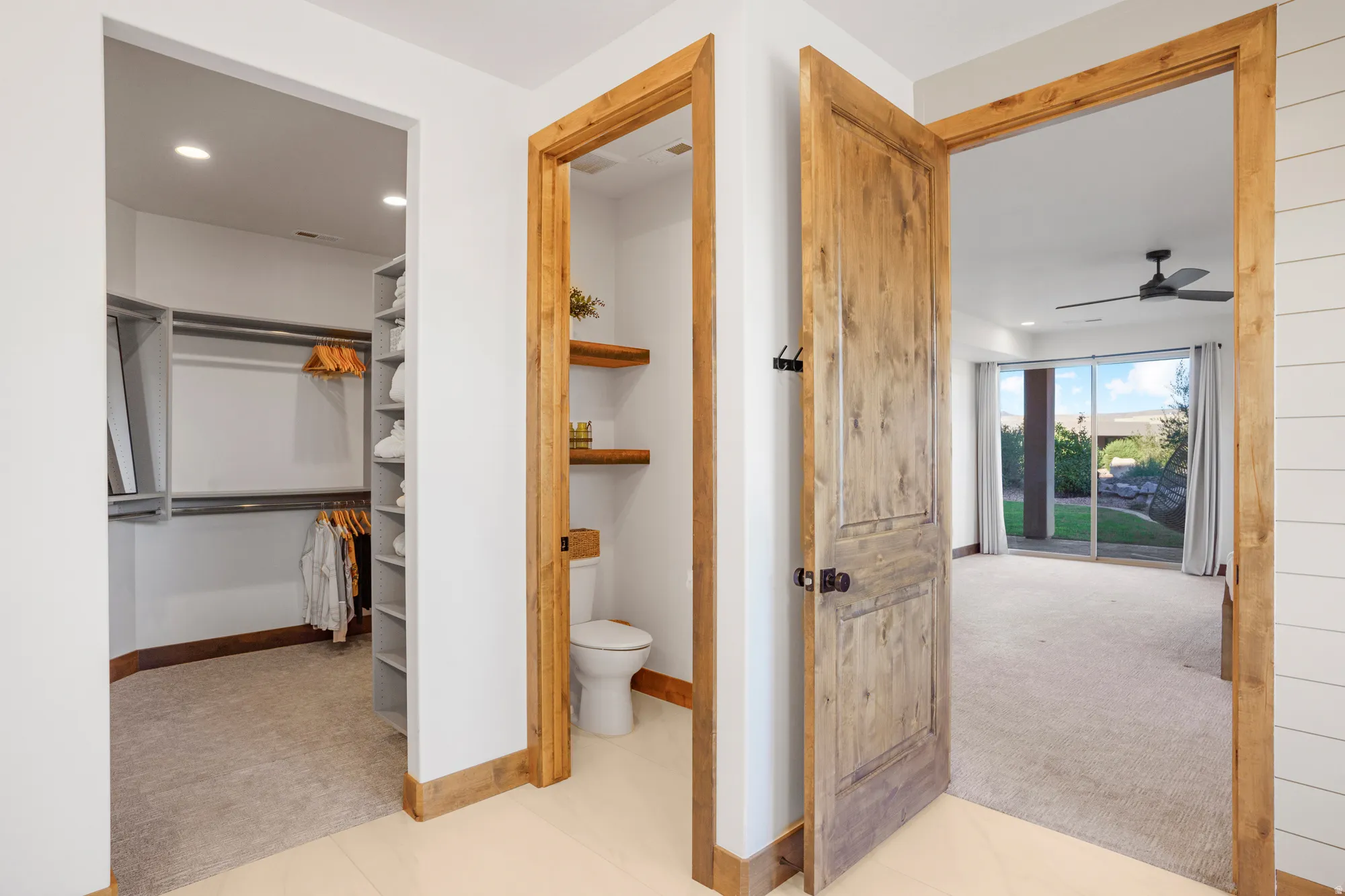 Carpeted room with a ceiling fan, sliding glass doors, and a private outdoor space