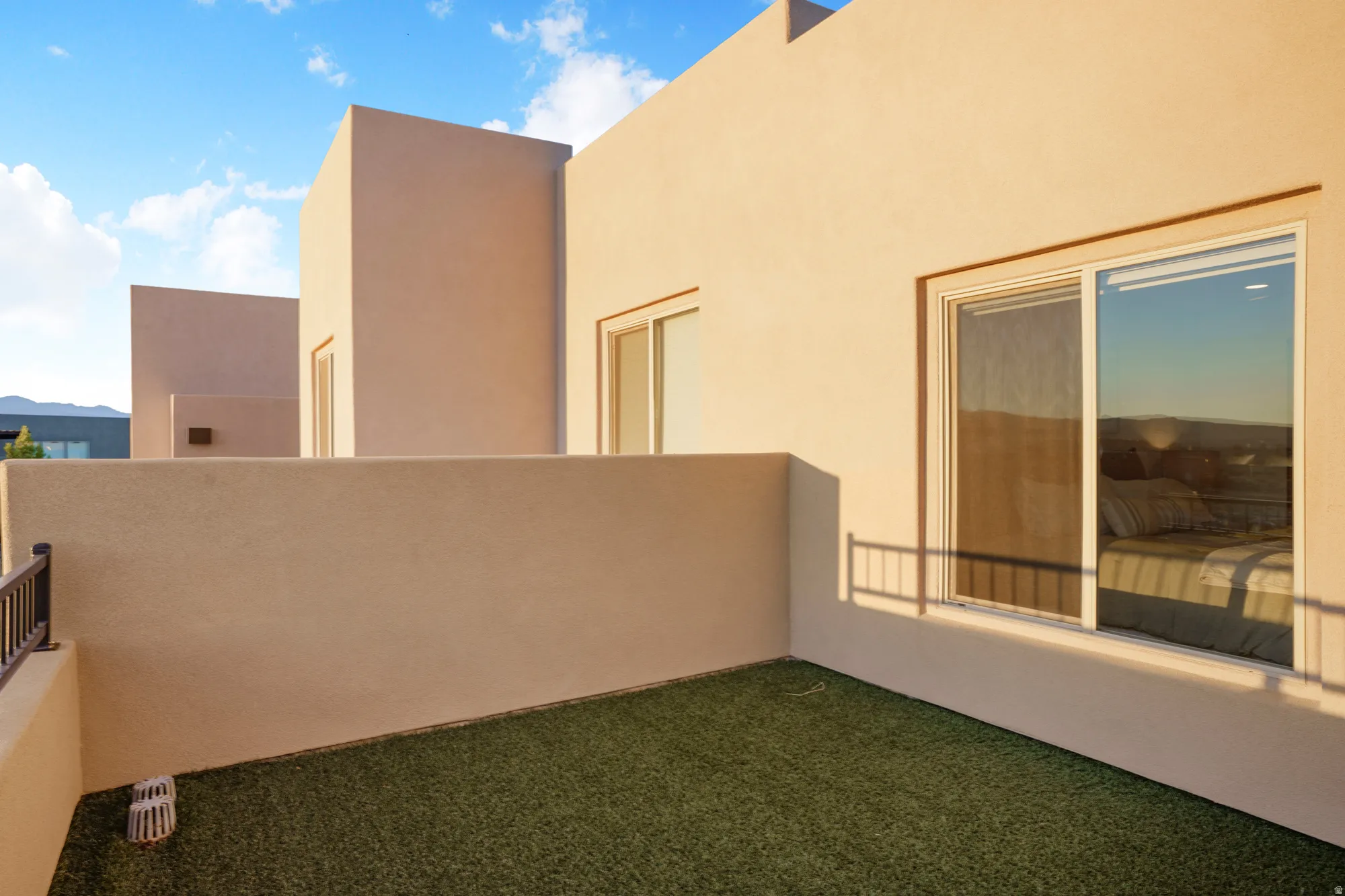 Stucco exterior with a private outdoor space, featuring artificial turf and a metal railing