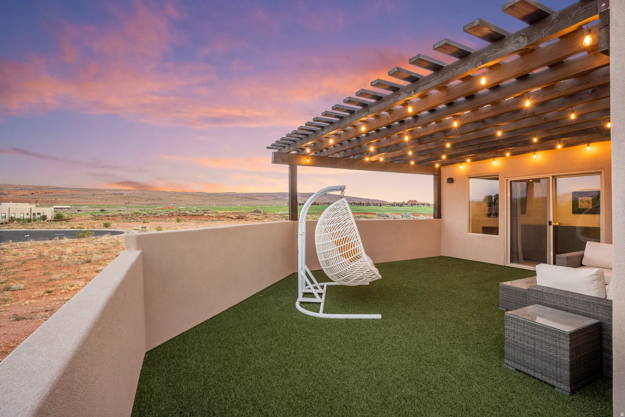 Terrace featuring a wood pergola with string lighting, simulated turf flooring, and a stucco perimeter wall