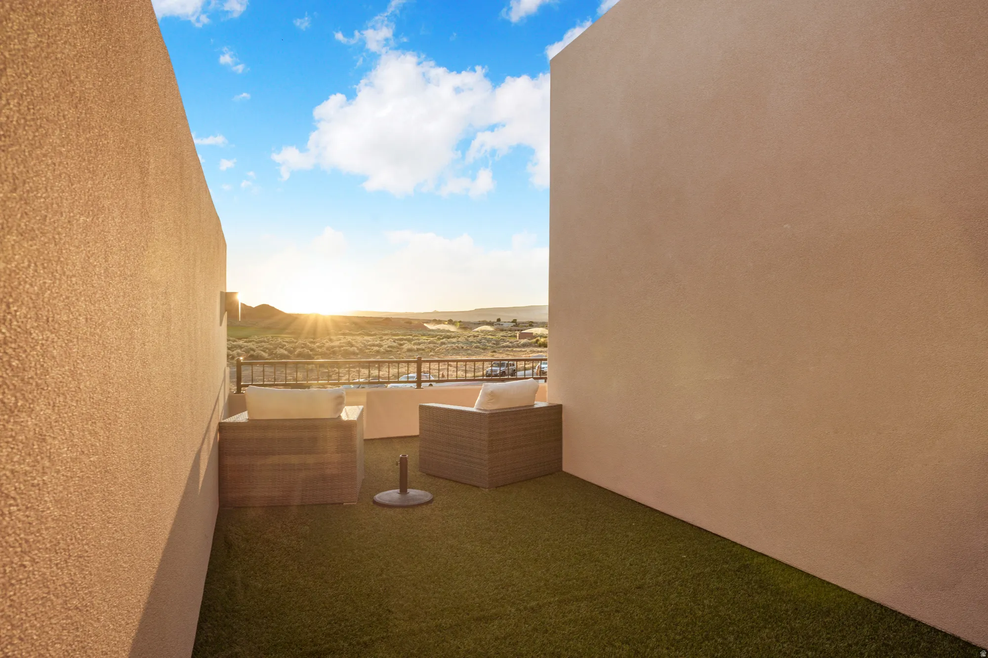 Rooftop patio with artificial turf, stucco walls, and a metal railing
